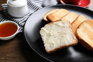 Slices of tasty toasted bread with butter and jam on wooden table, closeup