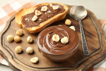 Toasts with tasty chocolate spread and hazelnuts on light table, closeup