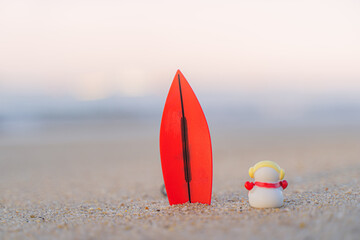 Sandy Christmas Snowman is watching the waves, standing on beautiful beach with a surf board - horizontal version in Patong Beach, Phuket, Thailand