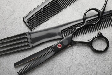 Different hairdresser's tools on grey table, flat lay