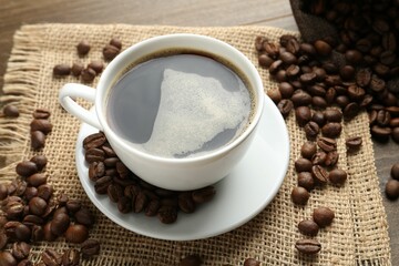 Aromatic coffee in cup and beans on table, above view