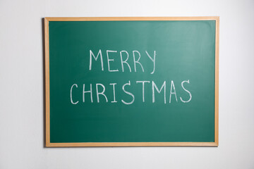 Obraz premium Green chalkboard with phrase Merry Christmas on wall