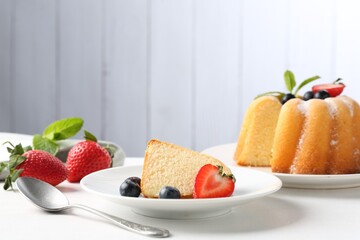 Tasty bundt cake with powdered sugar, berries and mint on white table, closeup