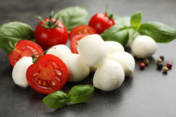 Mozzarella cheese, tomatoes, basil and peppercorns on grey table, closeup