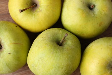 Many damaged green apples on wooden table, closeup