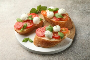 Tasty sandwiches with mozzarella cheese balls, tomato and basil on grey table