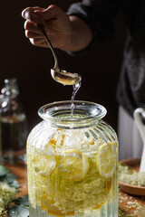 Close up of preparation of elderberry flower syrup,  soft light with deep shadows.