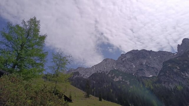 Timelapse the breathtaking beauty of towering Alps mountains in Steinberg area in Tyril accompanied by soft clouds against a backdrop of lush greenery, creating a serene and peaceful atmosphere.