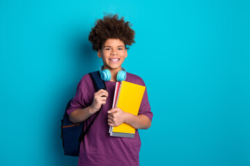 Young student holding notebooks with headphones in front of colorful background, showcasing stylish...
