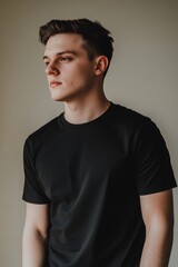 Black t-shirt mockup for men. Front view of male model wearing plain black tee on neutral background, perfect for apparel designs and branding.