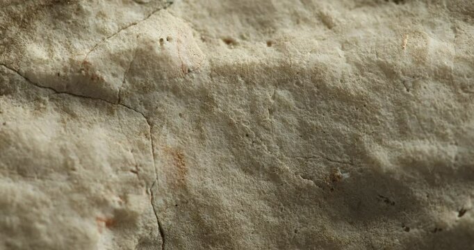Close-up of light sandstone surface with fine cracks and soft texture