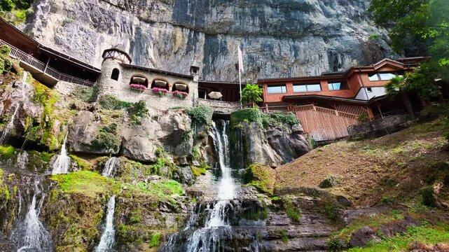 Scenic view of St. Beatus Caves entrance built into a cliffside with cascading waterfalls near Interlaken, Switzerland.