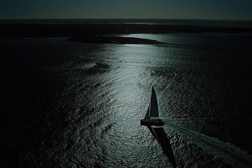 Dark water, moonlit sail.  A sailboat glides over tranquil waters at night