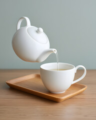 Pouring Tea into Cup on Wooden Tray