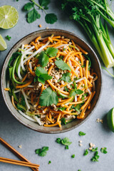 A vibrant Pad Thai noodle dish sits in a rustic bowl, garnished with herbs and lime, ready to be enjoyed. - Generative AI