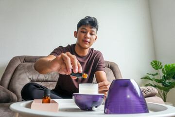 Young Man Drop Essential Oil into The Humidifier to Make Aromatherapy Refreshment for Relaxation