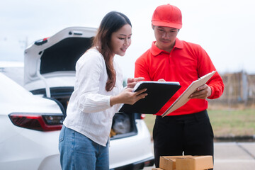 Middle-aged Asian female saleswoman delivers boxes of parcels online seller, hands packages to...