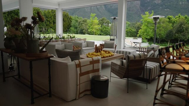 A beautiful setting in an undercover veranda of a luxury house showing expensive furniture and an exquisite view of a lush garden and large mountain