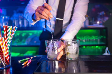Bartender preparing cocktail with ice and mint in a nightclub