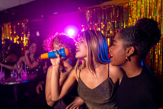 Friends singing karaoke at nightclub with microphone
