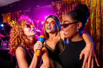 Happy multi ethnic friends singing karaoke in nightclub