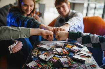 Friends fist bumping, starting a board game together