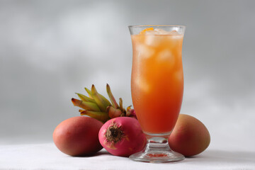 refreshing cocktail named fruit explosion served in tall glass surrounded by array of exotic fruits like mango
