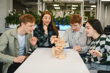 Friends playing engaging tabletop game, tower crashing down