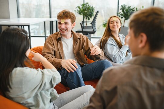 Friends playing guessing game with sticky notes on foreheads