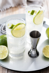 Gin Fizz cocktail with lime on wooden table