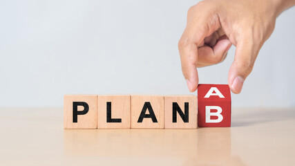 Businessman hand flipping wooden cube blocks with PLAN A change to PLAN B text on table background. strategy, analysis, marketing, project and Crisis concepts
