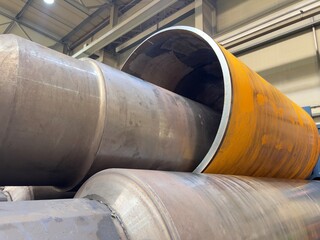 Close-up view of a metalworking process as a sheet of steel is rolled into a cylindrical shape by...