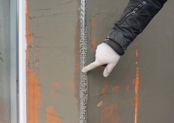 Window angle bead.  Close up on applying a coat of plaster, finish over the house window angle bead, reinforcing mesh outdoors.