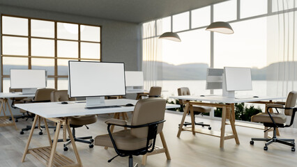 Blank screen computers on white table with swivel chairs on wooden floor in the office with large glass wall.