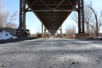 Asphalt road beneath modern steel bridge structure  
