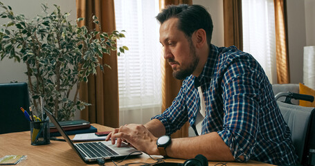 Serious handsome beard brunette man holds papers in hands typing number on cell phone finishing his work from home online closing computer work day finished.