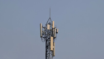 Telecommunications tower with antennas against a clear blue sky, representing modern tech infrastructure and connectivity