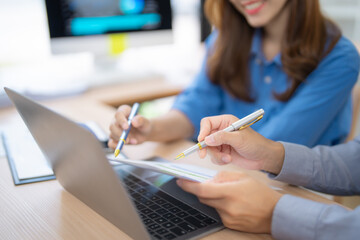 Business team analyzing financial charts and discussing statistics using laptop and documents at...