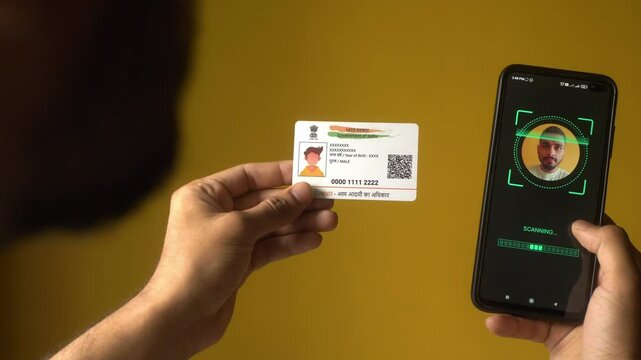 Indian nationality man scanning his face on a mobile phone for eKYC digital identity verification using Aadhaar card - Powered by Adobe