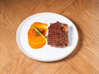 Grilled beef steak with sweet pepper sauce and asparagus on white ceramic plate