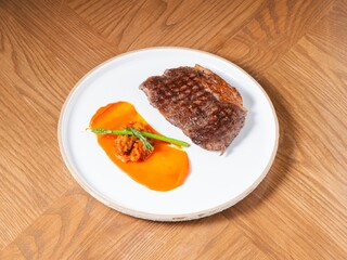 Grilled beef steak with sweet pepper sauce and asparagus on white ceramic plate