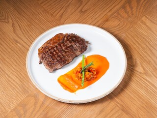 Grilled beef steak with sweet pepper sauce and asparagus on white ceramic plate