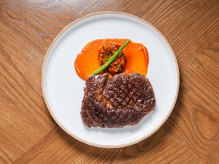 Grilled beef steak with sweet pepper sauce and asparagus on white ceramic plate