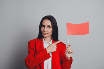 Successful businesswoman holding a red flag on a grey background showing a sign of alert, dressed...