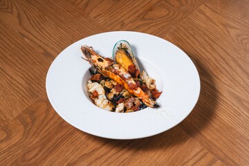 Seafood pasta with grilled river prawn, mussel and squid in rich sauce on white plate