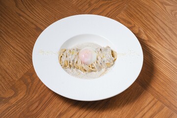 Truffle cream pasta with onsen egg and parmesan cheese on white plate