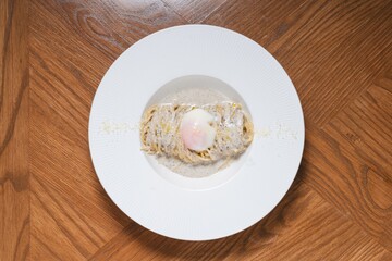 Truffle cream pasta with onsen egg and parmesan cheese on white plate