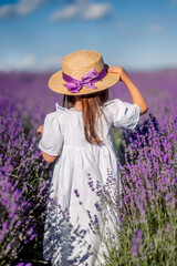 girl in a white dress and hat stands in a field of lavender