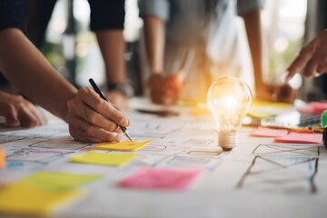 Fototapeta premium Creative UX Design Team Brainstorming Ideas with Light Bulb Symbolizing Innovation in Modern Office Workspace