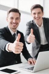 two men in suits giving thumbs up in front of a laptop